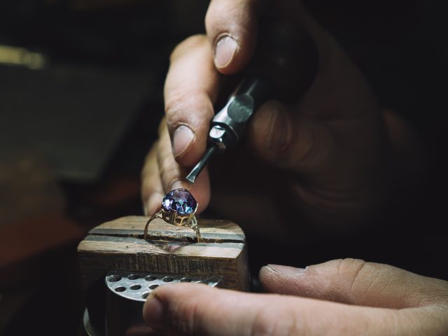 Close up of a goldsmith's hand making a gold or silver ring or a diamond using goldsmith's tools. For this work it takes precision and patience. Concept of: tradition, luxury, jewelry.