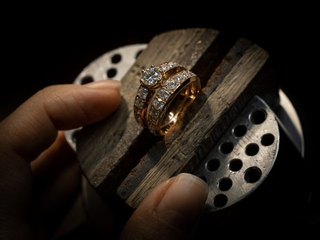 Jeweler puts diamond to golden wedding luxury ring.